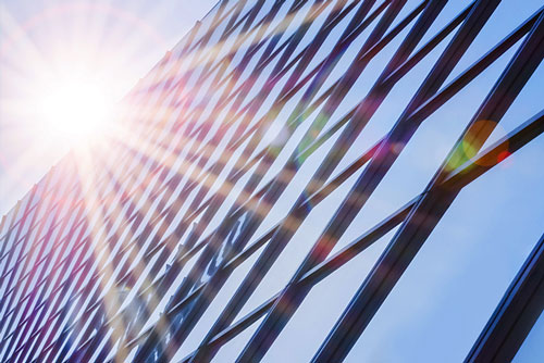 Sonnenstrahlen blitzen hinter Glasfassade hervor