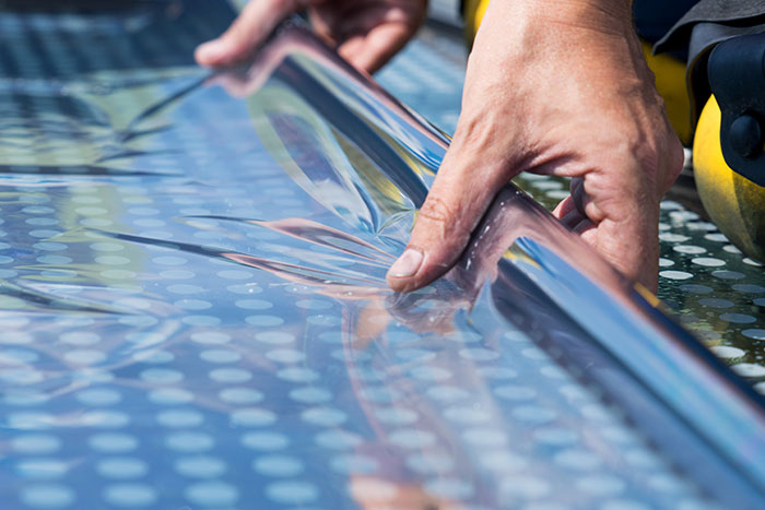 Mitarbeiter rollt UV-Folie aus.