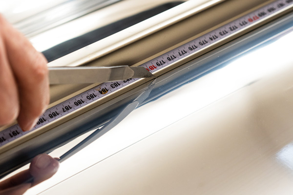 Spiegelfolie wird mit Cuttermesser auf Maß getrimmt